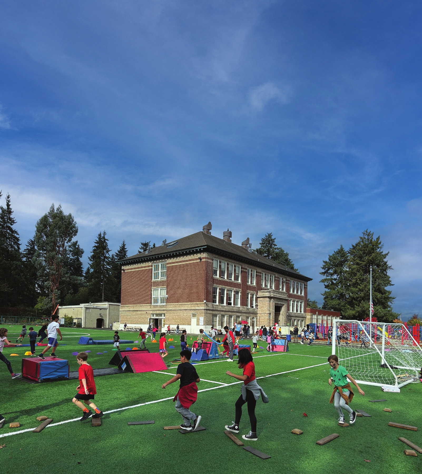 Children playing on McGilvra’s field at the fall Move-a-thon, with the brick school building behind them.